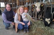 Eltern Lisa und Josef mit Sohn Theo beim Füttern der Rinder