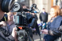 Videokamera richtet sich auf Person, die in Mikrophone spricht