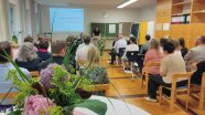 Personen sitzen auf Stühlen in einem Lehrsaal