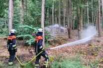 Feuerwehr spritzen mit Schläuchen Wasser in den Wald